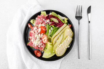 Healthy salad with pears and cheese in black bowl on white background for clean eating or recipe content