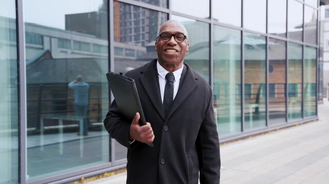Business professional smiles joyfully while holding a clipboard outside a modern office building in a vibrant urban setting during daylight hours
