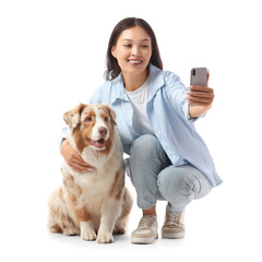 Young Asian woman with Australian Shepherd dog taking selfie on white background