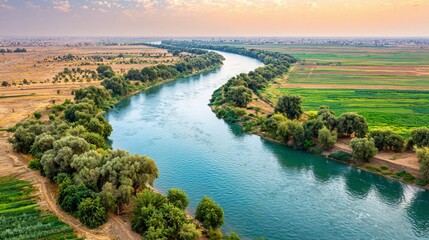Wide Aerial View of Serene River Winding Through Lush Green Farmland During Sunset