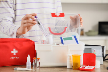 Young woman taking thermometer from first aid kits in kitchen, closeup