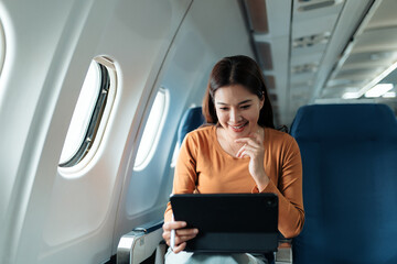 Happy passenger using digital tablet while traveling by airplane, enjoying entertainment during air travel © Crystal