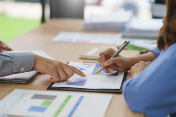 Business colleagues reviewing financial data, pointing at charts with pen, analyzing statistics and discussing growth