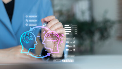 Close-up hand with stylus showing hologram of human head and AI brain connection, concept of artificial intelligence, machine learning, data analytics, knowledge transfer, and digital technology.