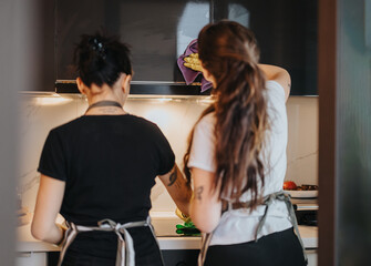Women working in a modern kitchen, wearing aprons and collaborating to cook. The scene highlights...