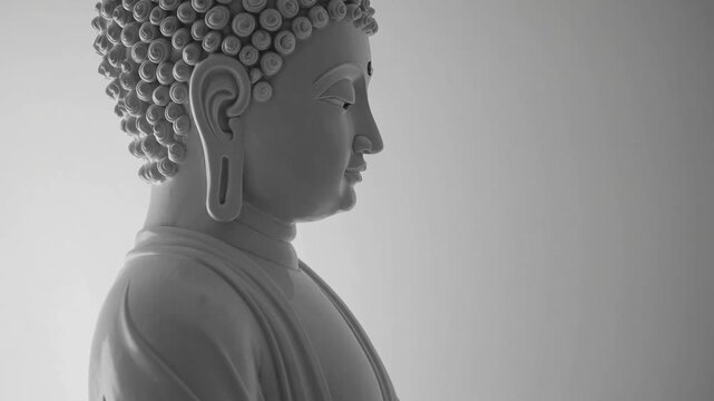 Profile perspective of meditative Buddha sculpture isolated on plain white backdrop providing ample area for text or ry