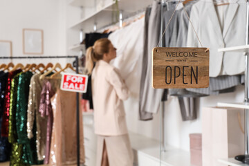 OPEN sign against female seller in clothes store, closeup
