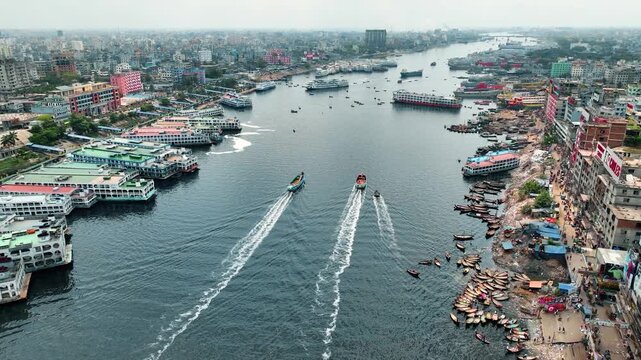 Dhaka, Bangladesh - 23 August 2025: Aerial view of boats sailing on the Buriganga River, contrasting the urban skyline with the bustling river activity.