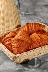 Freshly baked croissants resting in wicker basket on marble countertop