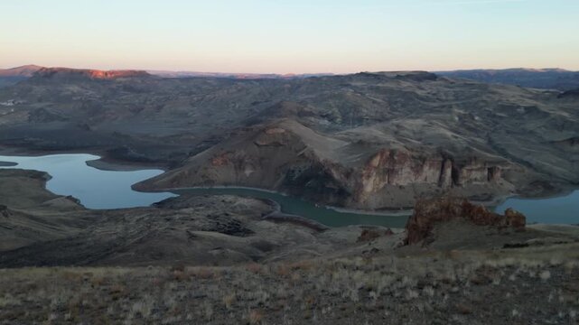 Leslie Gulch Cinematic drone shot of plateau edges and a winding river at dawn.