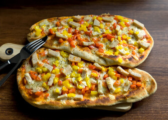 Close-up of Two Flame Baked Naan Bread Pizzas with Chicken Pieces, Cheddar Welsh Cheese and Yellow Red Bell Peppers