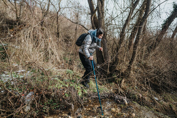 A single individual trekking through a forest area with a walking stick, exploring the outdoors on...