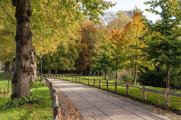 Cambridge, England. Walkways and gardens of King's College with autumn foliage and green lawns, part of the historic college grounds beside the River Cam