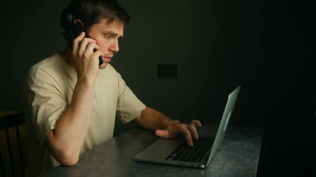 Man working from home getting increasingly frustrated with internet problems, calling tech support while trying to work on his laptop. Frustrated freelancer calling tech support for internet problems