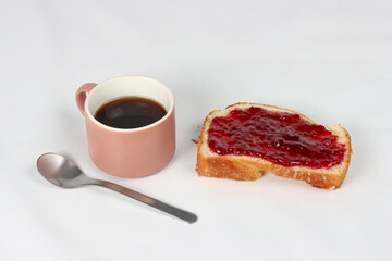 Cup of coffee with a slice of bread and jam on a white background