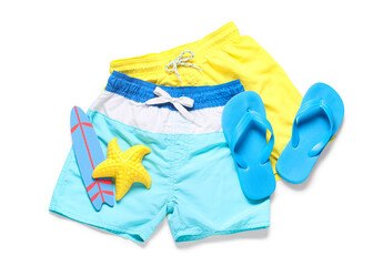 Children's swim shorts with flip-flops and toys on white background