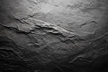 Dark, textured stone surface with subtle lighting variations, exhibiting a rough, uneven, and layered appearance