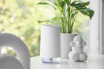 Air humidifier with decor and plant on shelf near window in room, closeup