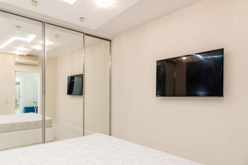 Modern Bedroom Interior with Wall-Mounted TV and Mirrored Closet