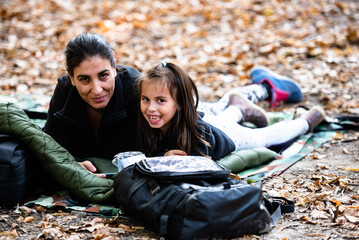 Mother and daughter relaxing in autumn forest during camping trip