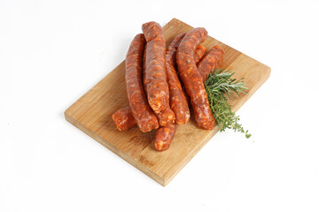 Group of raw merguez sausages on a wooden cutting board with a white background