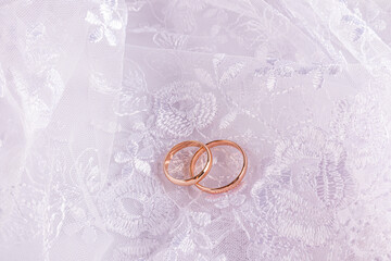 A pair of gold wedding rings on a white openwork background of the bride's dress. Beautiful wedding...