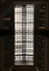 Architectural view of a modern skylight ceiling with geometric steel frame and glass panels. Interior roof structure allows natural light to pass through.