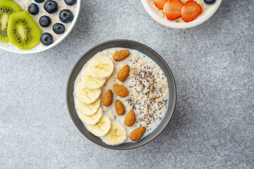 Topview of banana almond chia oatmeal bowl surrounded by other fruit bowls