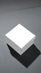 A simple white box sits atop a muted gray surface, casting a defined shadow.
