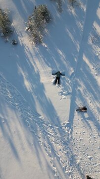 Teenager girl making a snow angel in a snowy forest