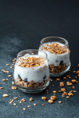 Parfaits with granola and yogurt in glass on dark  background