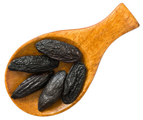 Tonka beans in the wooden spoon, isolated on white background, top view.