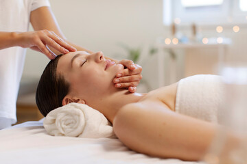 Serene lady receiving calming facial rub, professional masseur touching female forehead and chin,...