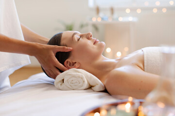 Calm young lady receiving head massage, resting at modern luxury spa in calm and serene atmosphere,...