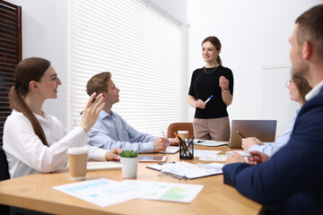 Business coach giving presentation to group of people in office