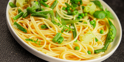 Spaghetti vegetables green peas, broccoli, string beans, kohlrabi vegetarian pasta tasty snack fresh delicious gourmet food background on the table rustic top view copy space vegan food