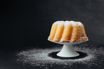 Golden bundt cake on white stand with dark stone background