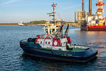 Powerful tugboat maneuvering in an industrial harbor