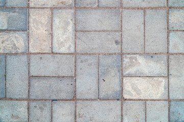 An overhead close-up shows interlocking concrete pavement stones with grains of sand filling the seams, creating an textured, neutral surface suitable for various backgrounds and design overlays.