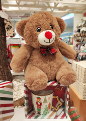 A soft brown teddy bear toy in a shop window. A holiday card for the New Year holiday.