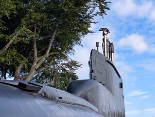 Submarine on display surrounded by trees under a bright blue sky