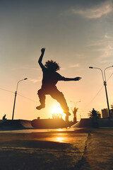 Backlight Silhouette of skater on skateboard jumping sunset sky at skate park, Skateboarding on street during sunset time. © rjankovsky
