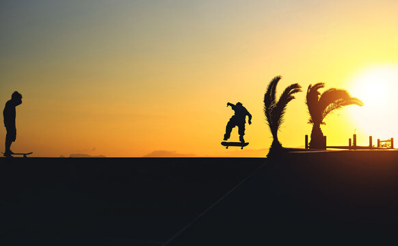 Backlight Silhouette of skater on skateboard jumping sunset sky at skate park, Skateboarding on street during sunset time. - Powered by Adobe