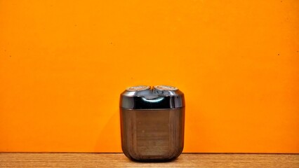Electric shaver on orange background. Concept of personal care and grooming.