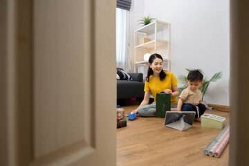 An Asian mother and son do activities together at home, such as dressing up, playing games, playing ball, and drawing.