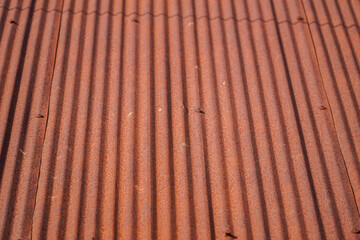 A textured surface reveals weathered metallic ridges, casting linear shadows and forming a...