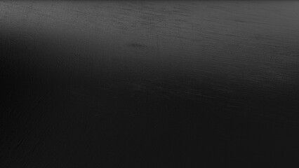 Abstract close-up of glossy black metallic foil texture with subtle reflective highlights and deep...