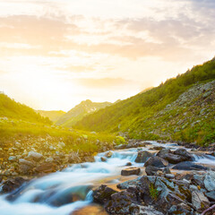 mountain river rushing over a stones at the sunset, evening mountain scene