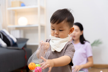 An Asian mother and son do activities together at home, such as dressing up, playing games, playing ball, and drawing.