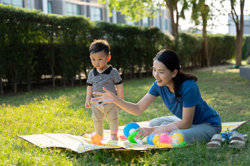 Asian mother and son doing activities together in the grass
